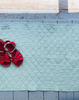 Red sandals on a light blue doormat with a wooden floor background